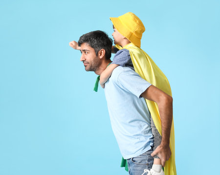 Father and little son dressed as superheroes on color backgroundの写真素材