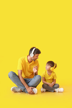Father and little son listening to music on color backgroundの写真素材