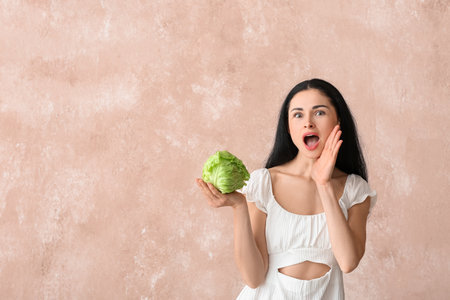 Young woman with fresh cabbage on color backgroundの写真素材