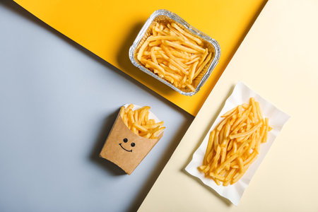 Creative composition with tasty french fries on color background