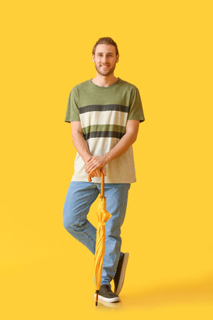 Handsome young man with umbrella on color backgroundの写真素材