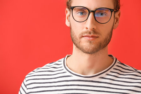 Young man wearing eyeglasses on color background