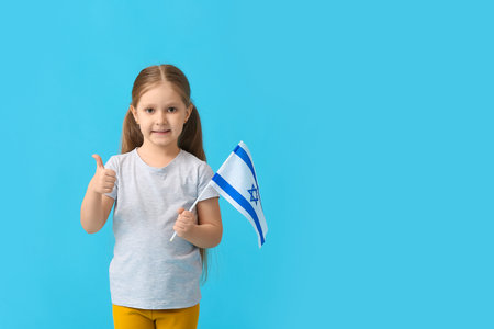 Little girl with the flag of Israel showing thumb-up on color backgroundの写真素材