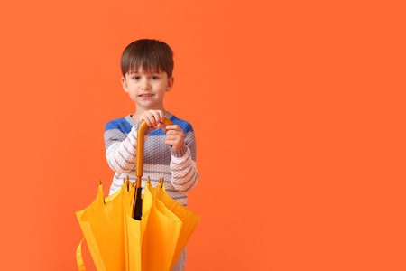 Cute little boy with umbrella on color backgroundの写真素材