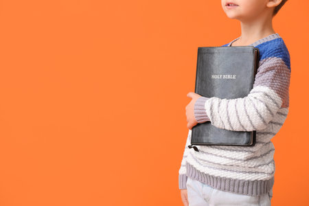 Little boy with Bible on color backgroundの写真素材