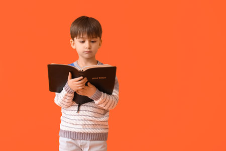 Little boy with Bible on color backgroundの写真素材