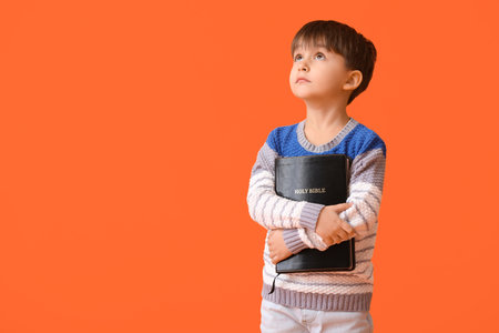 Little boy with Bible on color backgroundの写真素材