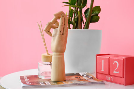 Wooden hand with magazine and decor on table near color wallの写真素材