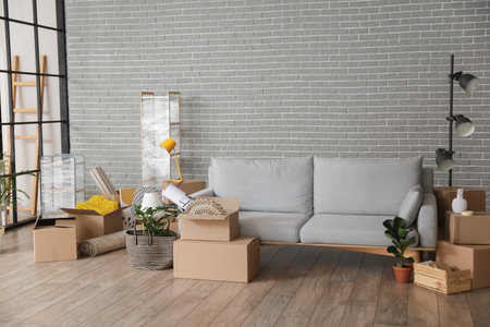 Cardboard boxes with accessories and sofa in room on moving dayの写真素材