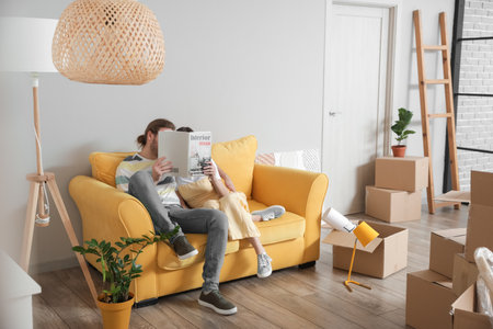 Young couple reading magazine in their new house on moving dayの写真素材