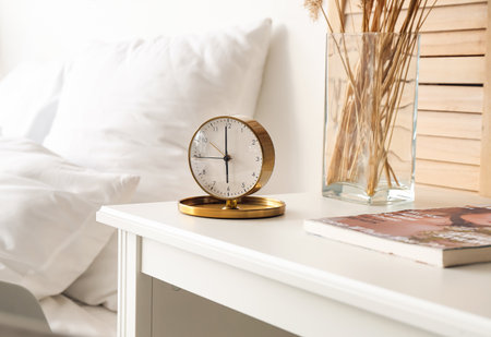 Stylish alarm clock on table in bedroom