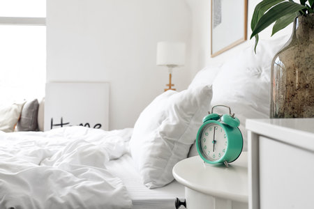 Stylish alarm clock on table in bedroomの写真素材