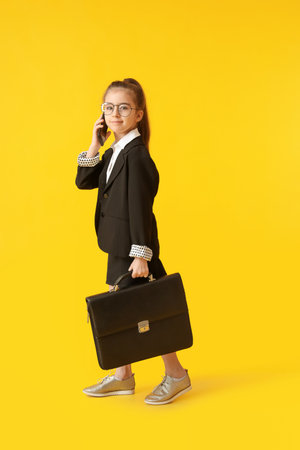 Cute little businesswoman talking by mobile phone on color backgroundの写真素材
