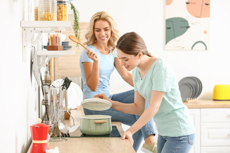 Beautiful young sisters cooking soup in the kitchen