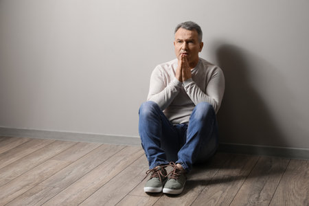 Religious mature man praying in roomの写真素材