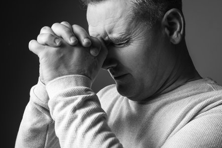 Black and white portrait of praying mature man on dark backgroundの写真素材