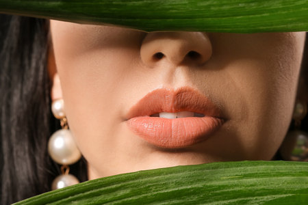 Beautiful young woman with tropical leaves on dark background, closeupの写真素材