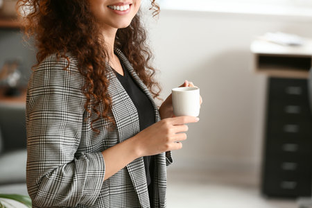 Beautiful young woman with cup of coffee in the kitchenの写真素材