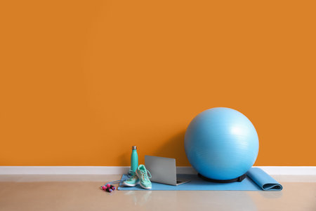 Set of sports equipment and laptop on floor near color wallの写真素材