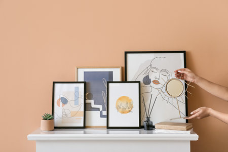 Young woman with mirror and pictures on mantelpiece near color wall