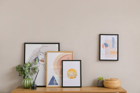 Stylish pictures on shelf near light wall