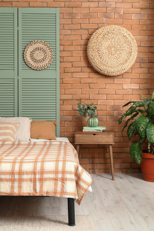 Interior of stylish bedroom with folding screen near brick wallの写真素材