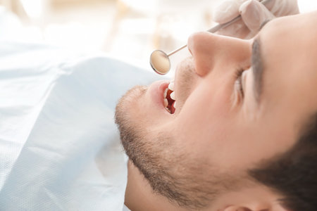 Dentist examining teeth of young man in clinicの写真素材