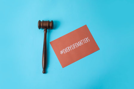 Judge gavel and paper sheet with hashtag #EVERYLIFEMATTERS on color background