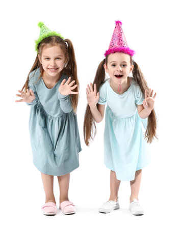 Cute little sisters in party hats on white backgroundの写真素材