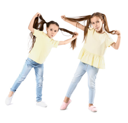 Cute little sisters eating lollipops on white backgroundの写真素材
