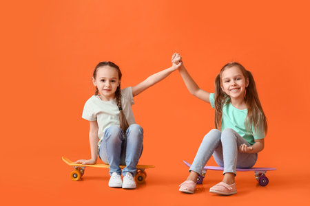 Cute little sisters with skateboards on color backgroundの写真素材