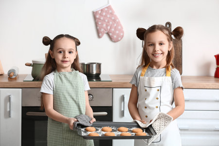 Cute little sisters with tasty cookies in the kitchen