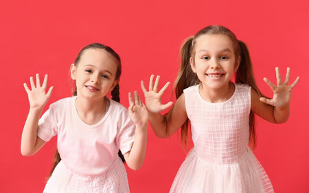 Cute little sisters on color backgroundの写真素材