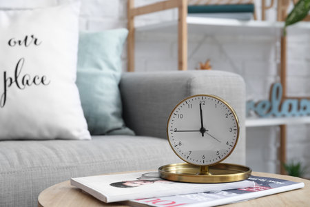 Alarm clock with magazines on table in living roomの写真素材