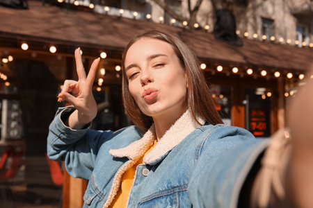 Beautiful young woman taking selfie outdoorsの写真素材