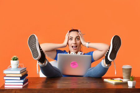 Surprised female programmer using laptop on color backgroundの写真素材