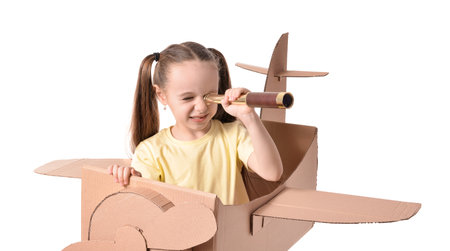Little girl playing with spyglass and cardboard airplane on white backgroundの写真素材