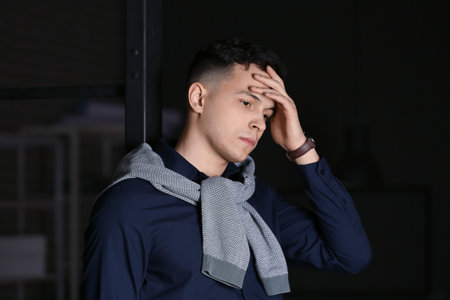 Depressed young man at home in the eveningの写真素材