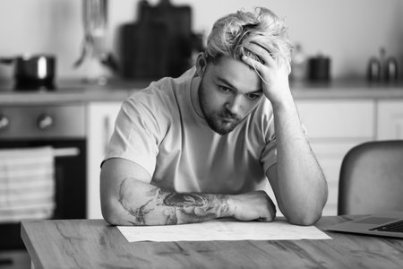 Black and white portrait of depressed young man at home
