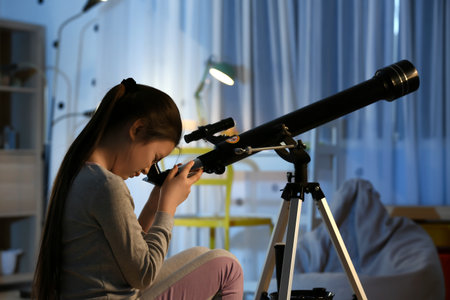 Cute little girl with telescope looking at the stars in the eveningの写真素材