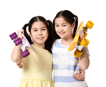Cute Asian sisters with skateboards on white backgroundの写真素材