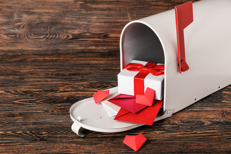 Mailbox with letters, gift and hearts on wooden background. Valentine's Day celebration