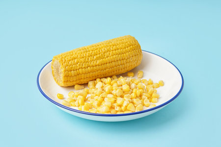 Plate with corn cob and kernels on blue backgroundの写真素材