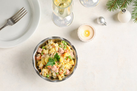 Bowl of tasty Olivier salad, burning candle and glass of champagne on light backgroundの写真素材