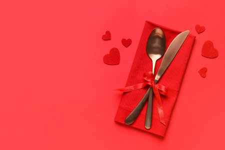 Cutlery with bow and hearts on red background. Valentine's Day celebrationの写真素材