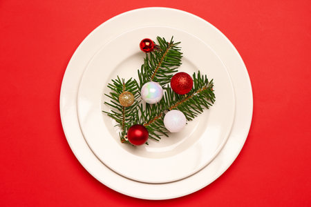 Christmas table setting with fir branch and balls on red backgroundの写真素材