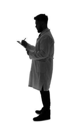 Silhouette of male doctor writing in clipboard on white backgroundの写真素材