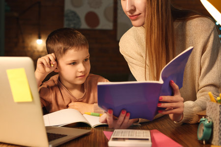 Little boy with his mother doing homework at home late in the evening