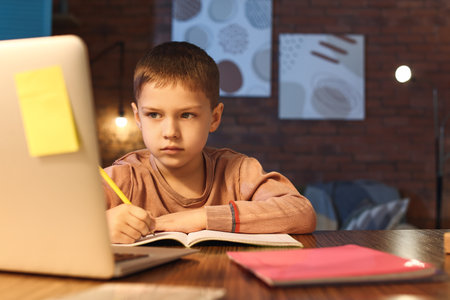 Little boy doing homework at home late in the eveningの写真素材