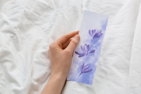 Woman with bookmark on bed, closeupの写真素材